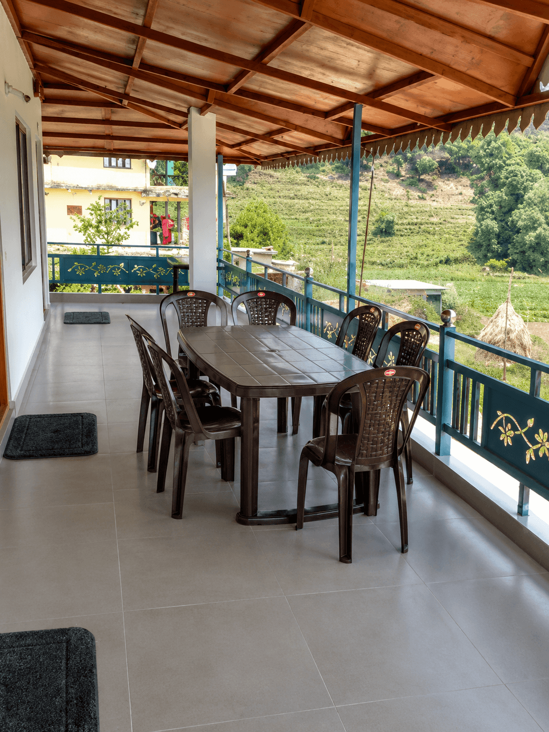 Covered balcony seating area with hillside greenery
